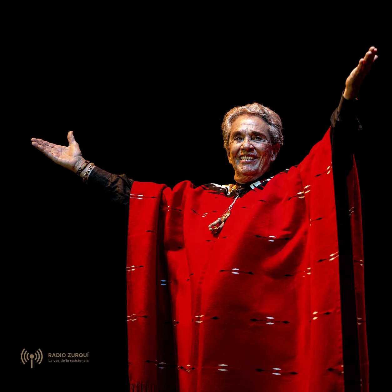 Chavela Vargas vestida de rojo y con los brazos abiertos en la cita del día del 5 de agosto de Radio Zurquí